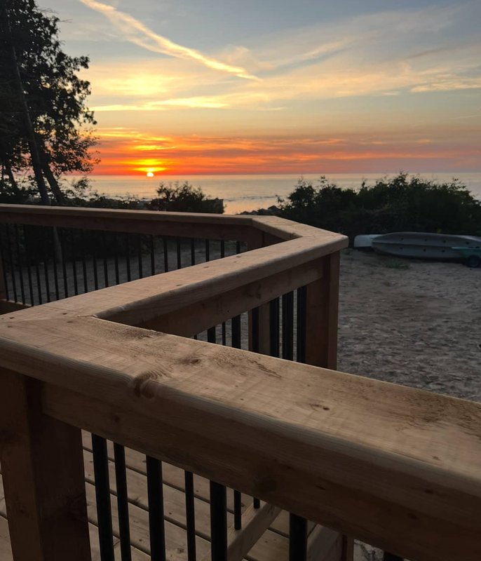 Deck railing at sunset over water