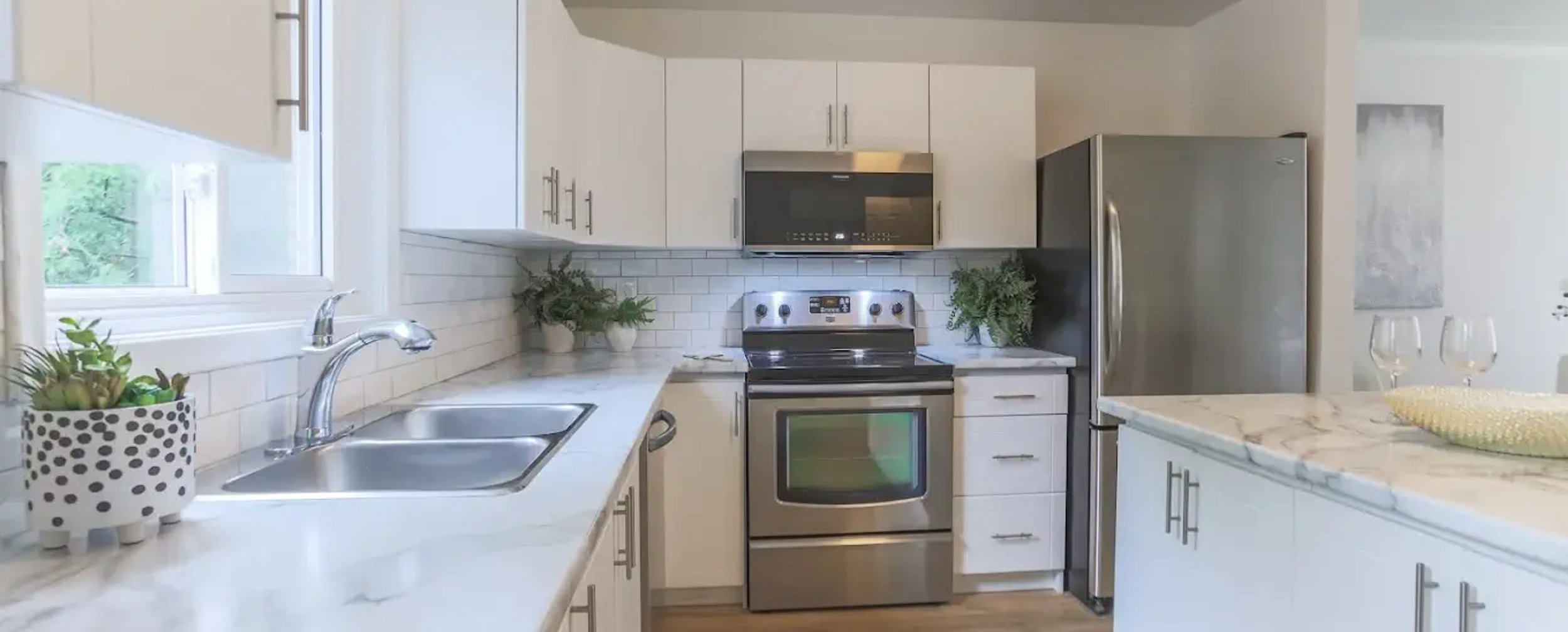 Renovated white kitchen with quartz countertops and stainless steel appliances